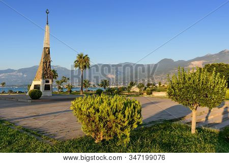 Turkey, Hatay - August 24, 2019: The Monument At Iskenderun With Trees And Mountains