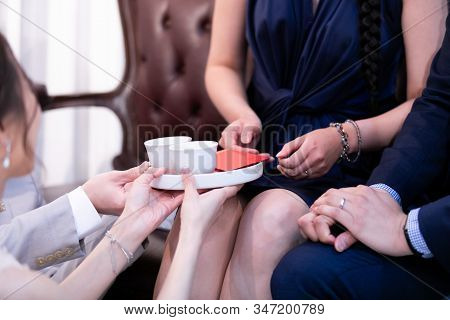 In Chinese Wedding Tea Ceremony, Young Couple Kneel While Serving Tea As Sign Of Respect And Parents
