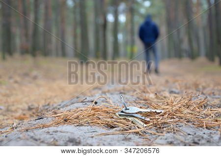Young Man Loses His Keys Bunch On Russian Autumn Fir Wood Path. Carelessness And Losing Keys Concept