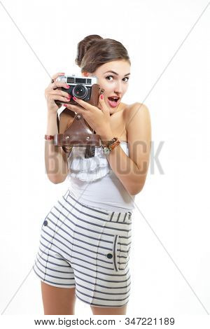 Beautiful girl takes pictures with retro photo camera, over white. Young pretty woman witn vintage equipment, pin up style