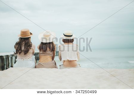 Three Woman Wearing Straw Hat  Sitting On Vacation Sea Beach