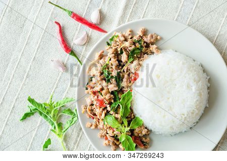 Rice Topped With Stir-fried Pork And Basil In Dish On Tablecloth.
