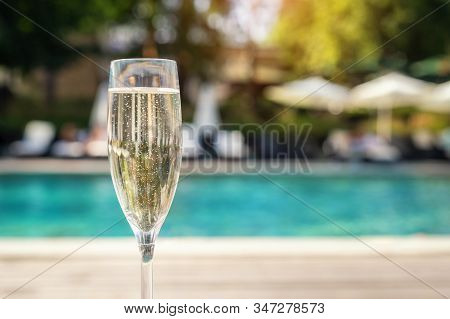 Close-up White Champagne Or Prosecco Glass Against Poolside At Luxury Resort Hotel During Vacation. 