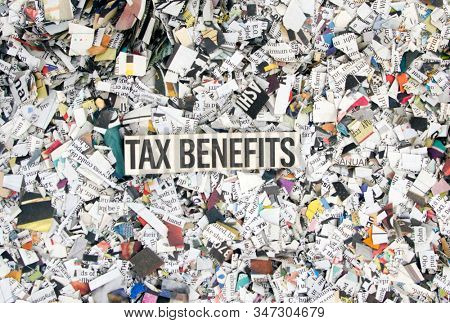Newspaper confetti from above with the word TAX BENIFITS background