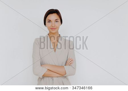 Prosperous Successful Business Lady Wears Elegant Wear, Crosses Hands While Stands Indoor At Office 