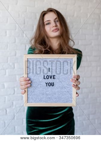 Beautiful Woman In Green Dress Holding A Felt Letter Board With The Words I Love You On White Bricks