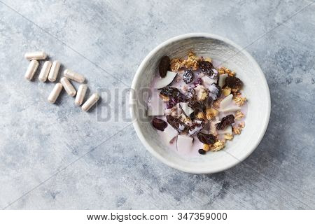 Bowl Of Granola With Yogurt, Nuts, Cranberry And Cocoanut. Sport Supplements ( Carnitine Capsules ) 