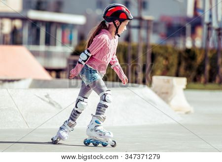 little cute girl riding on roller skates on the bike path
