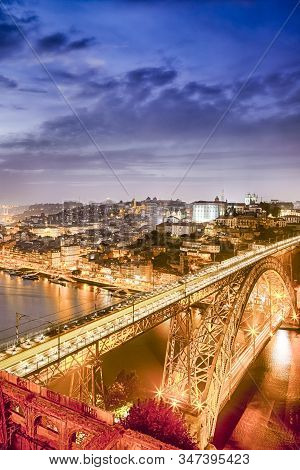 Golden Hour At Porto City In Portugal With Dom Luis I Bridge In Foregound With Lights Of Passing Tra