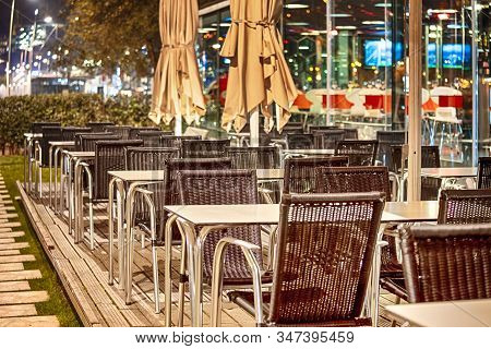 Wicker Chairs In One Of The Caffees Of Porto City In Portugal At Dusk.horizontal Image