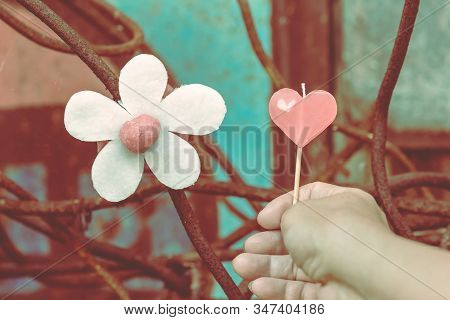 A Red Heart-shaped Candle On Woman's Hand And An Artificial Flower Made Of White And Red Candles Wit