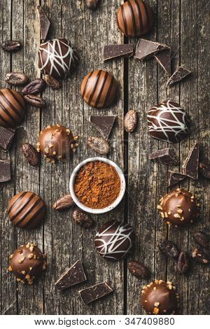 Praline bonbons. Chocolate truffles and cocoa powder on old wooden table.