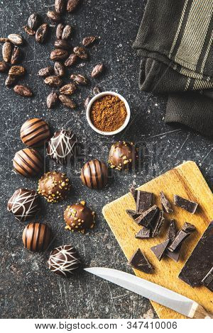 Praline bonbons. Chocolate truffles and cocoa powder on old kitchen table.