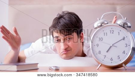 Man in bed frustrated suffering from insomnia with an alarm cloc