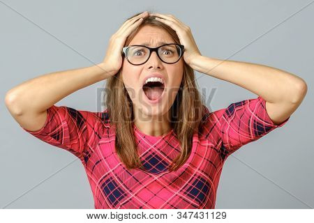 Portrait Of Stunned Woman In Red Dress, Holding Hands On Head