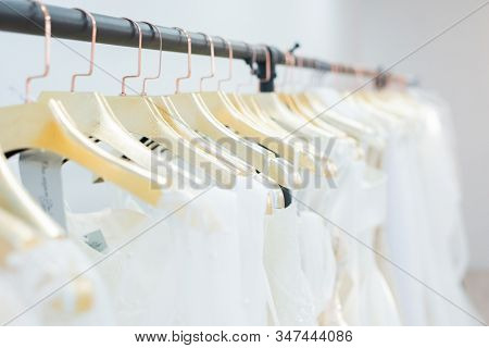 Clothing rack with wedding dresses on golden hangers in row, wedding show room concept
