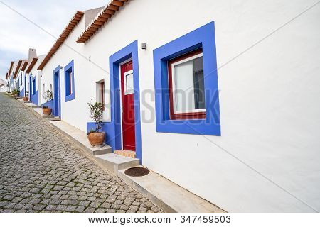 Cobblestone Street With Blue And White Traditional Colorful Homes And Buildings In The Algarve Town 