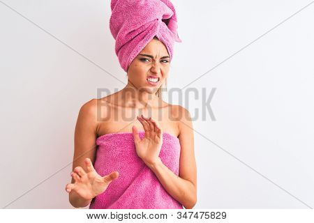 Young beautiful woman wearing shower towel after bath over isolated white background disgusted expression, displeased and fearful doing disgust face because aversion reaction. With hands raised. Annoy