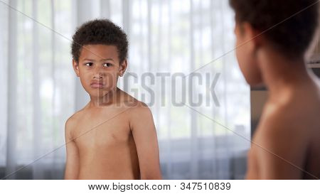 Unhappy Little African American Boy Looking In Mirror, Suffering Insecurities