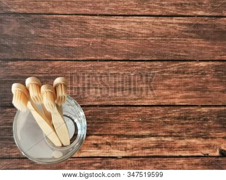 A Family Set Of Four Wooden Toothbrushes In A Glass On Wooden Background With Copy Space