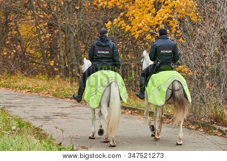 Mounted Police In Autumn City Park, Back View. Two Russian Police Officers On Horseback Patrol The P