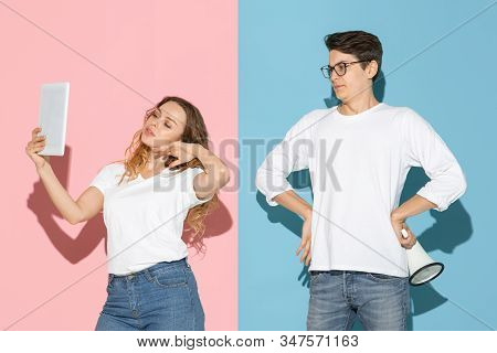 Shes Taking Selfie, Hes Trying To Pay Attention. Young And Happy Man And Woman On Pink, Blue Backgro