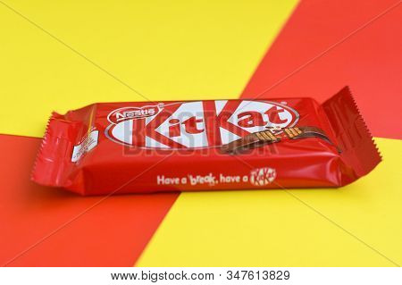 Kit Kat Chocolate Bars In Red Wrapping Lies On Yellow And Red Background. Kit Kat Created By Rowntre