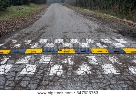 Black And Yellow Speed Bump Line  On Concrete Road Surface. An Old  Traffic Safety Speed Bump On A  
