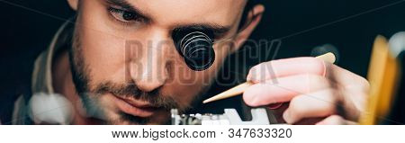 Panoramic Shot Of Watchmaker In Eyeglass Loupe Working With Wristwatch Isolated On Black