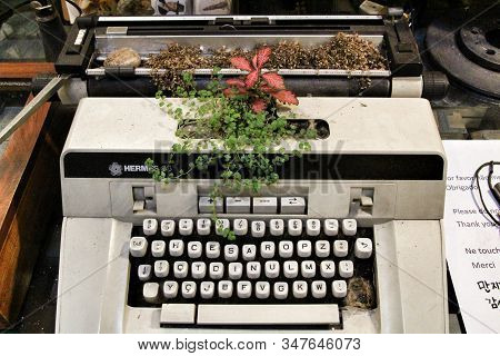 Porto, Portugal- January 3, 2020: Vintage Hermes Typewriter With Plant On It For Sale In An Old Ware