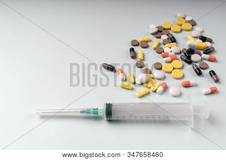 Medicine Pills And Disposable Syringe Closeup On Blue Background. Health Pharmacy Pharmacology Conce