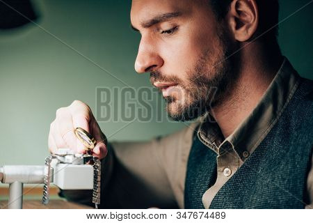 Side View Of Watchmaker Using With Magnifying Glass For Wristwatch On Movement Holder