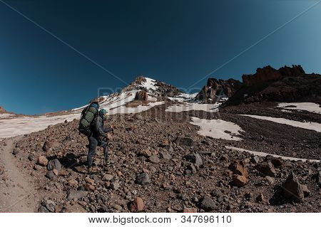 Man Standing On The Rocky Path Looking Up To The Mountain