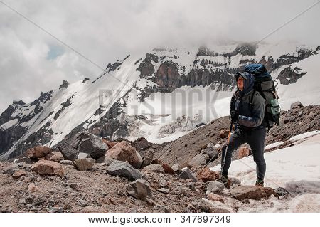 Man Standing On The Rock Around The Snow Remnants In The Mountains