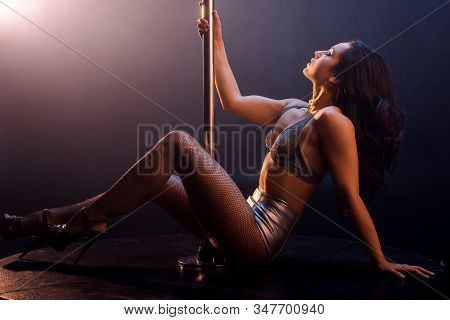 Side View Of Seductive Stripper In Lingerie Dancing Striptease Near Pole On Black