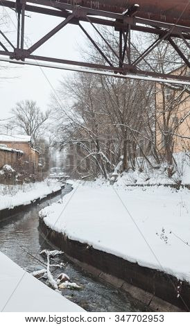 Urban Stream In Winter. The Lybid River (kyiv, Ukraine) In The Snow. Elevated Pipeline Across The Ri