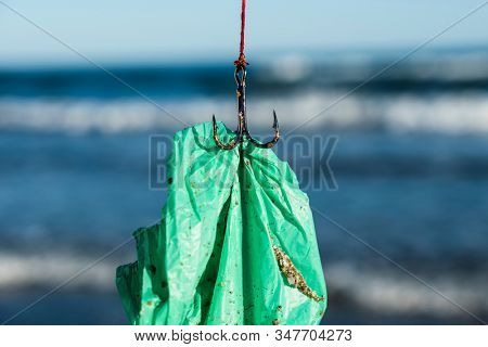 closeup of a used green plastic bag in a fish hook, freshly fished in the ocean