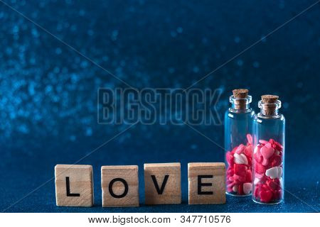 Two Glass Bottles With Heart-shaped Sugar Sprinkles On Gliter Blue Background. Valentines Day Concep