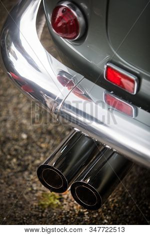 Close Up Vertical Image Of The Red Tail Light And Exhaust Pipes Of A White Classical Vintage Car.