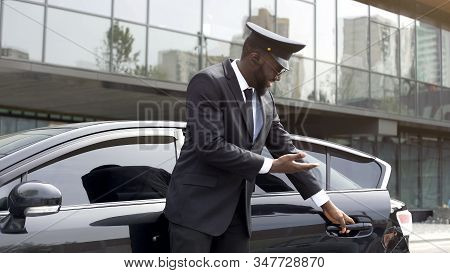 Attentive Taxi Driver Politely Opening Car Door, Inviting Client To Sit Down