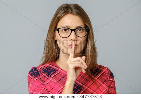 Portrait Of Emotional Woman Holding Index Finger At Her Lips, Saying Shh
