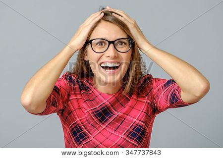 Portrait Of Stunned Woman In Red Dress, Holding Hands On Head
