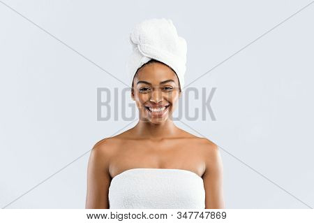 Portrait Of Happy Young Black Woman Wrapped In Bath Towels Over Grey Studio Background