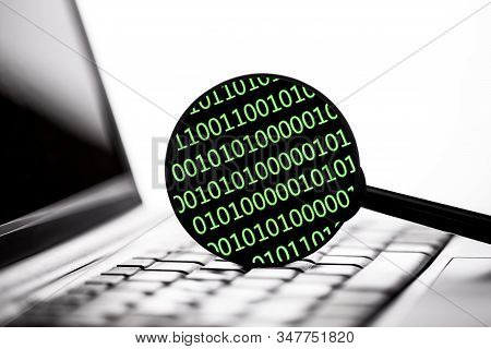 Green Binary Code. Magnifying Glass On Laptop Keyboard. Internet Security Zero One Code Background.