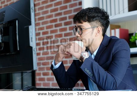 Young Asian Businessman Concentrate On Working With Computer At Office, Asian Office Man Holding Cof