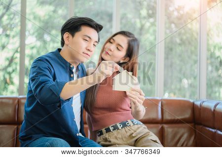 Portrait Of Happy Couple Inserting Coin In Homebank