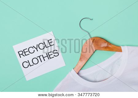White T-shirt R Lying On Green Turquoise Background And Paper Card With Text Recycle Clothes