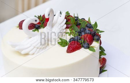 White Birthday Cake With 2 Swans Made Of Sugar Mastic With Fresh Berries Of Kolubniki And Blueberrie