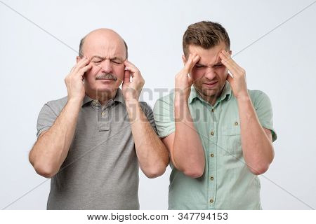 Displeased Men Keep Fore Fingers On Temples, Frown Faces In Discontent, Suffer From Headache.