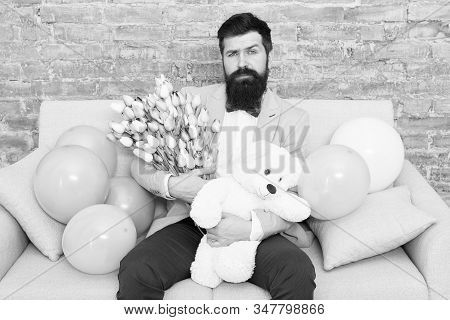 Best Boyfriend Ever. Romantic Man With Flowers And Teddy Bear Sit On Couch Waiting Girlfriend. Roman